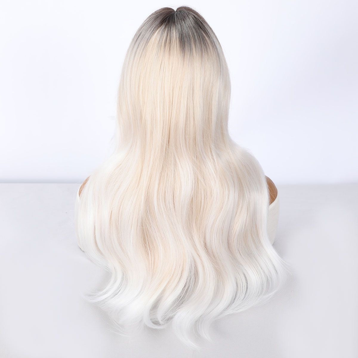 Long blonde wavy wig back view with dark roots and layered wave length