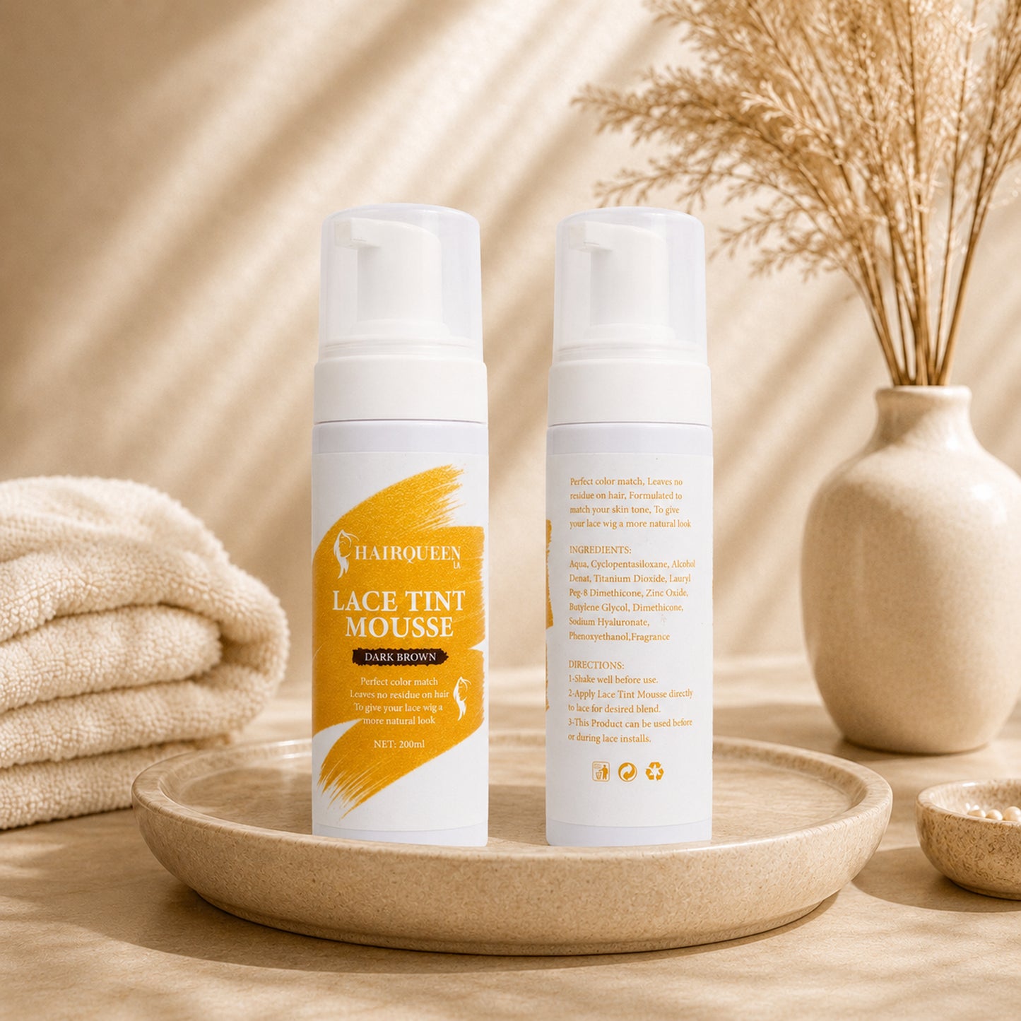 Two lace tint mousse bottles on round tray with folded towel