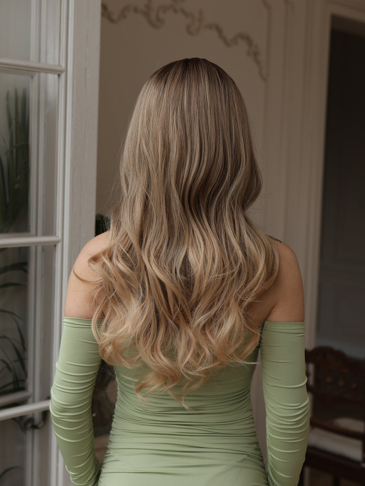 Long wavy wig back view with dark roots, light brown hair and blonde icy highlights