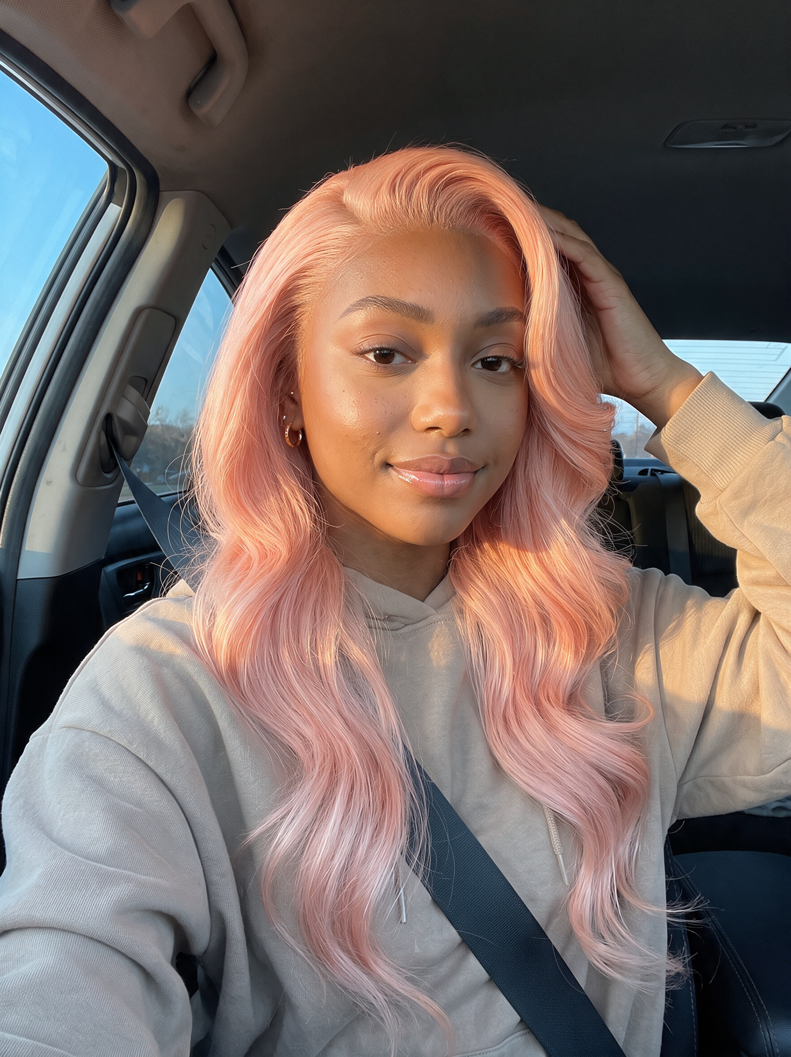 Light pink wavy wig with natural hairline, worn at shoulder length, center part.