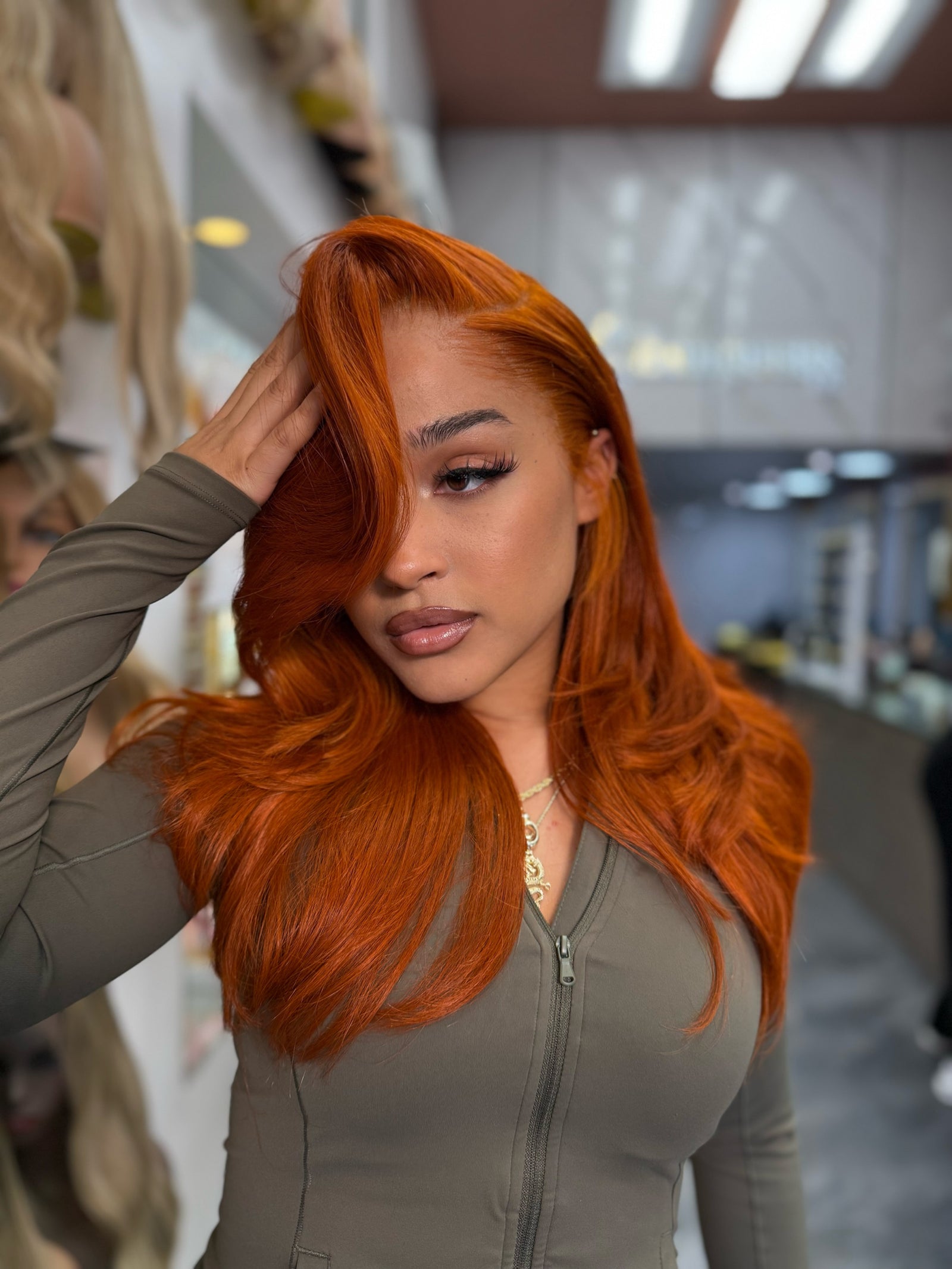 Long wavy ginger-orange lace wig with side part, styled over shoulders