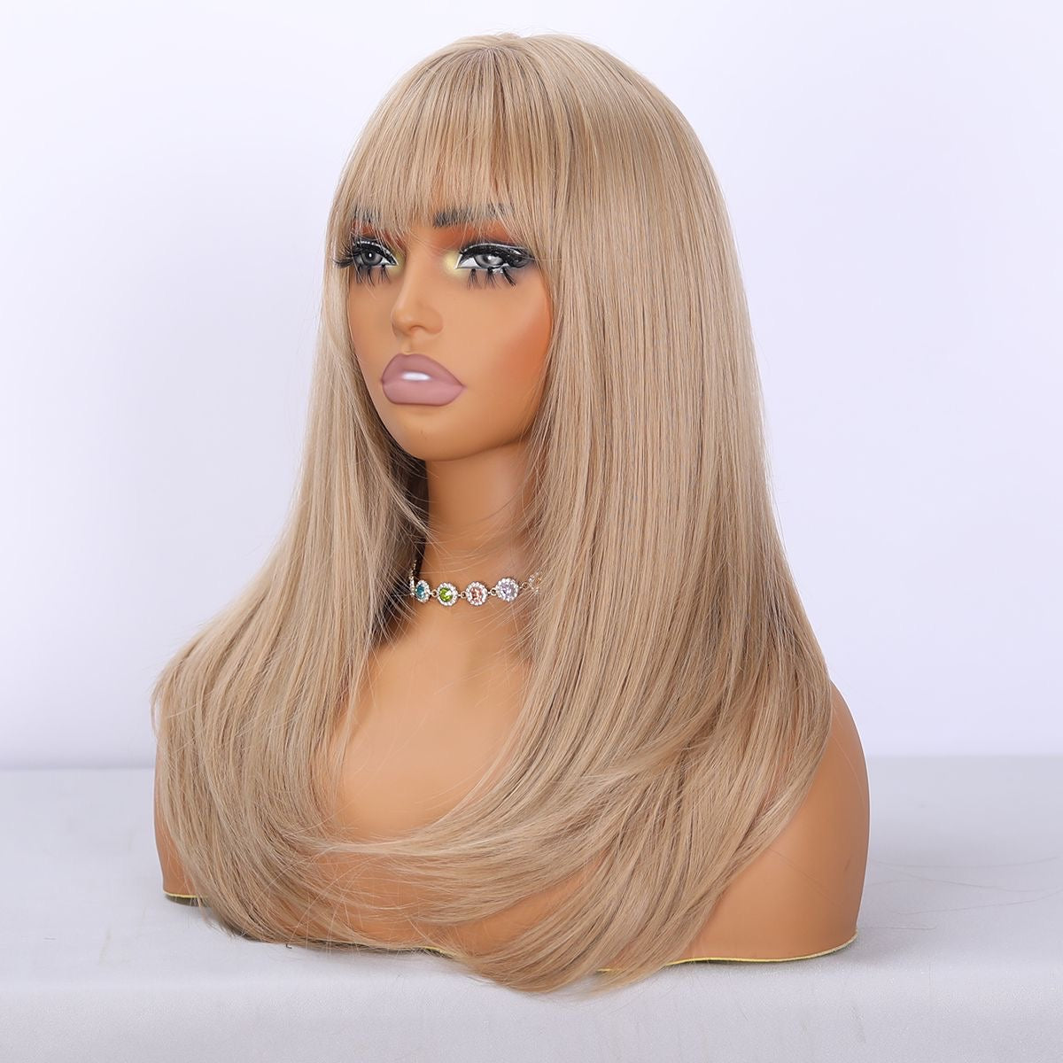 Warm-toned blonde synthetic wig with layered bangs and long straight hair, side view