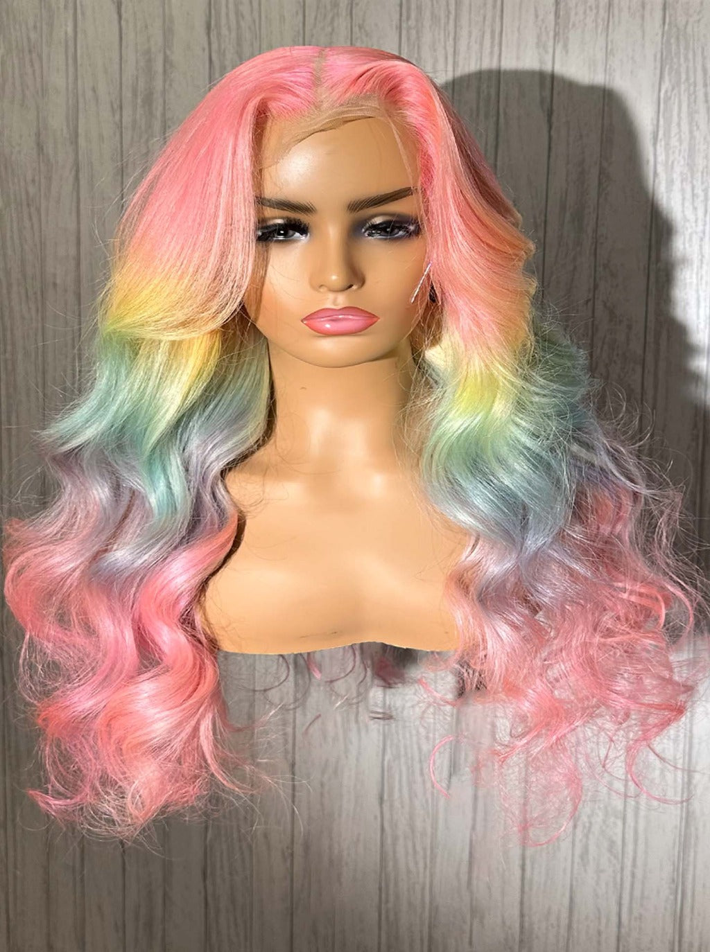 Pastel rainbow wig with a center part and voluminous layered waves in pink and mint
