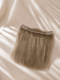 Hair line topper with lace base and long, straight blonde-brown hair strands.
