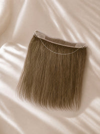 Hairline topper showing straight brown strands with curved transparent lace attachment