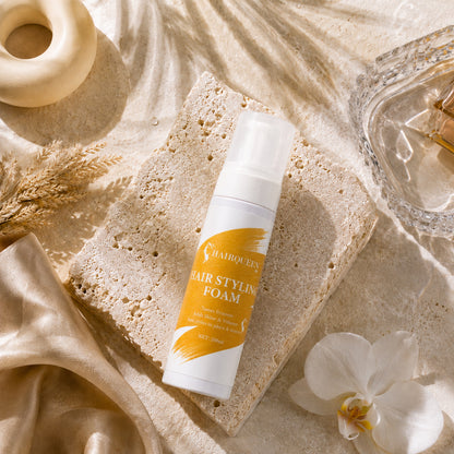 HQLA hair styling foam pump bottle lying on a sponge block with flowers nearby