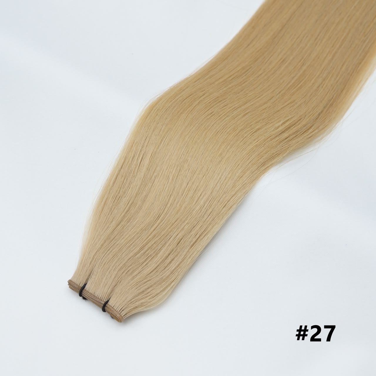 Tape-in hair extensions, straight strands in honey blonde #27 with visible tape clips