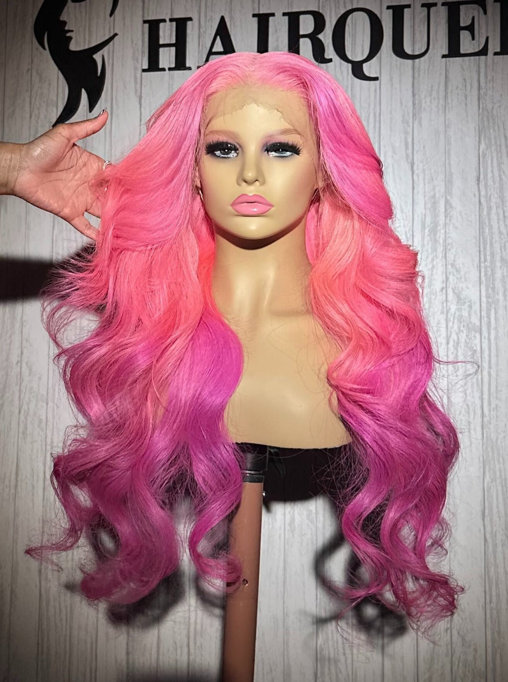 Long pink wavy wig on mannequin with voluminous curls and side-swept hair