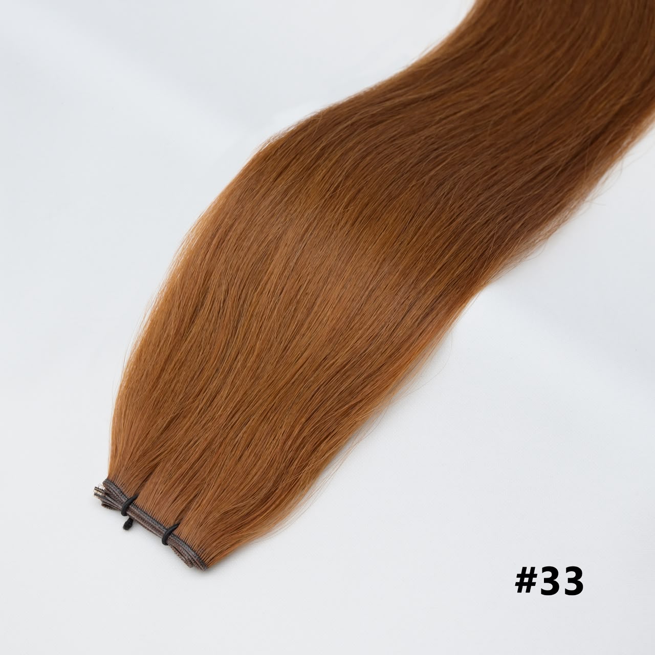 Tape-in hair extensions, straight strands in auburn #33 with visible tape clips