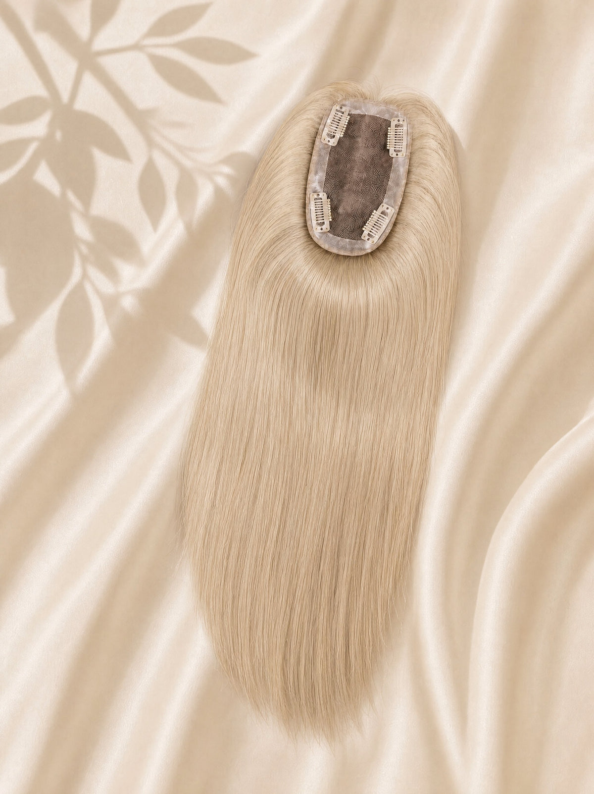 Clip-in mono base hair topper with long straight ash-blonde strands on beige cloth