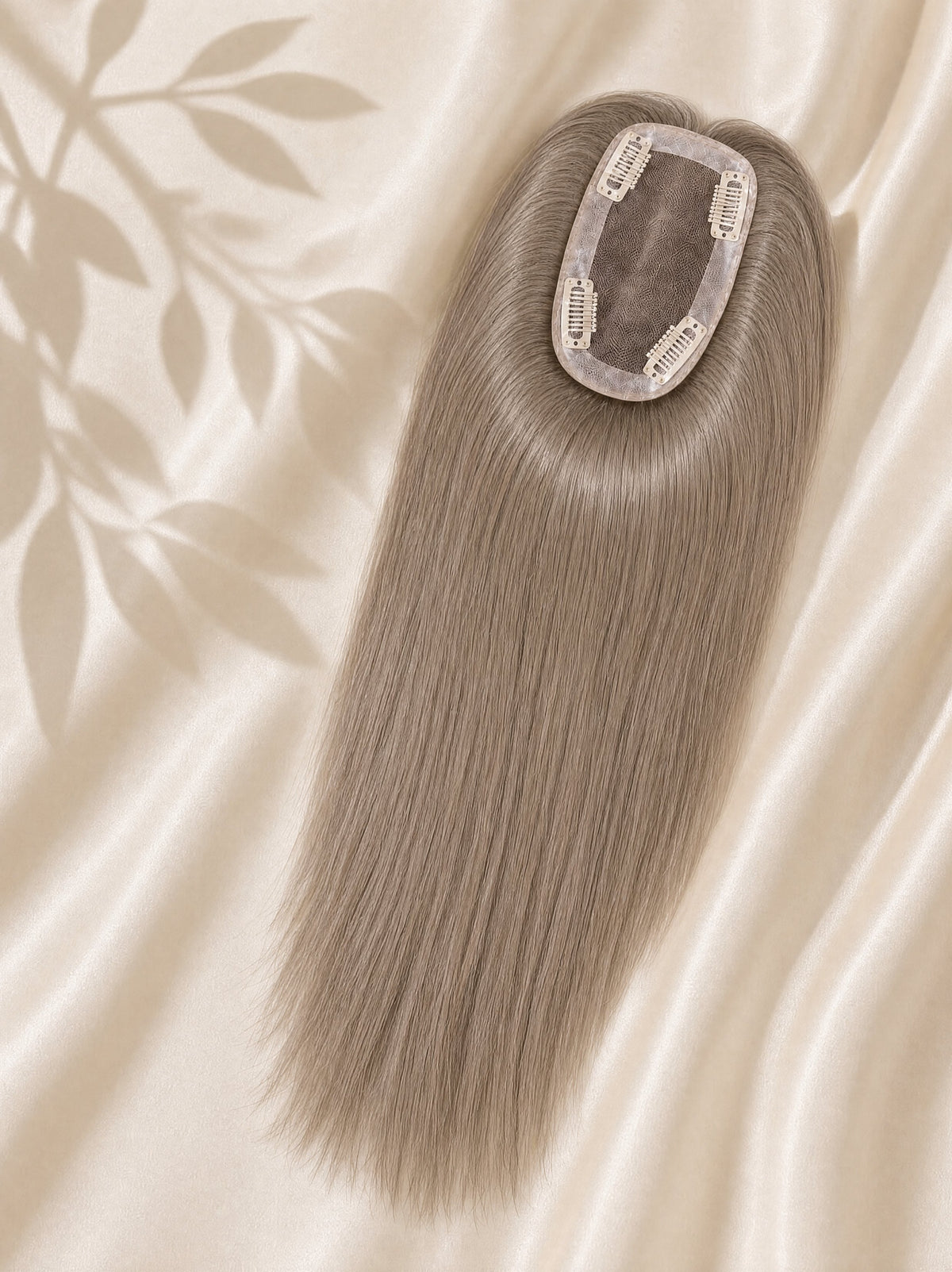 Clip-in mono base topper with smooth ash-gray hair strands, shown on beige fabric