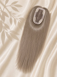 Clip-in mono base topper with smooth ash-gray hair strands, shown on beige fabric