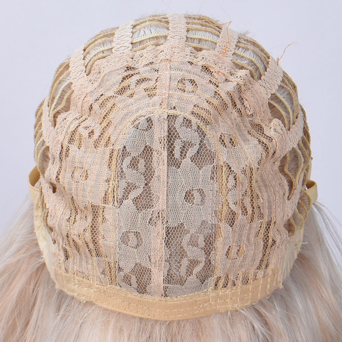 Wig cap close-up with beige netting and attached blonde hair strands