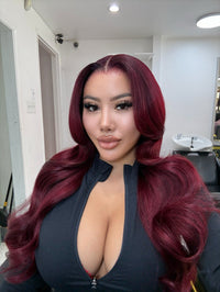 Long burgundy wavy wig with deep side part and voluminous waves