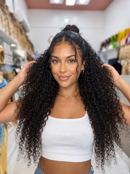 Curly lace wig with dark ringlet hair and center-parted top bun on model