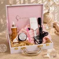 Hair extension kit in a white box with gold handle, pink bonnet, bottles, comb, and corded tool