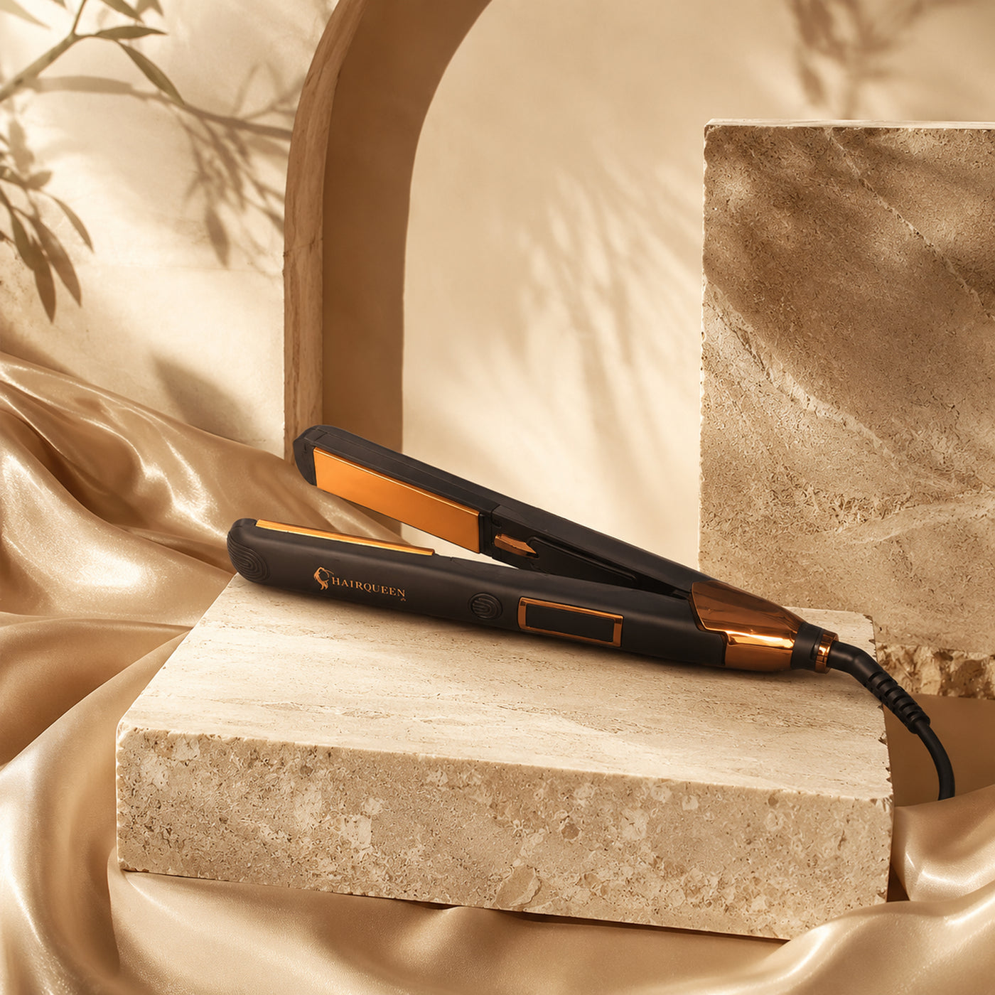 Black flat iron with gold heating plates and cord, angled on stone pedestal