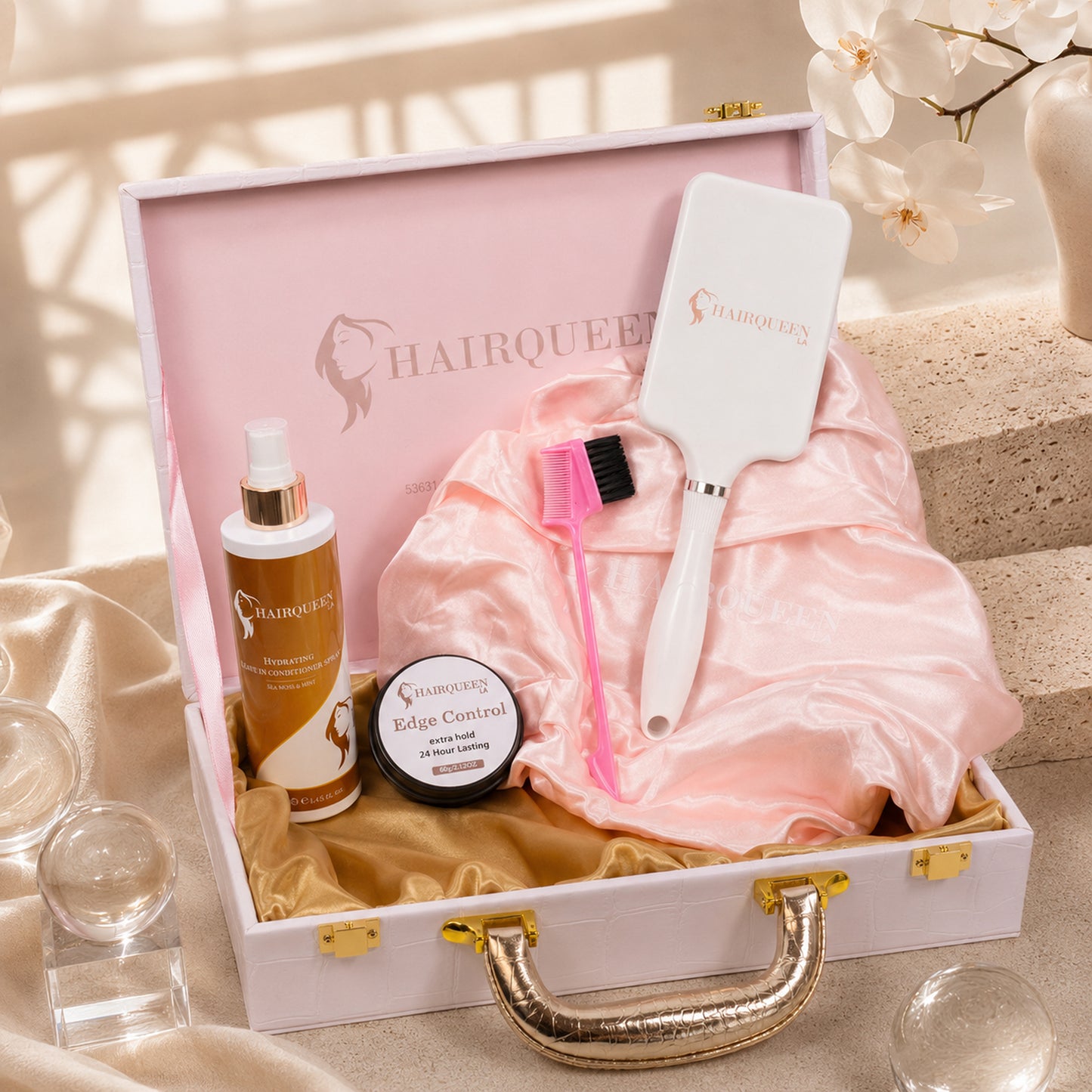 Hair extension care kit with pink satin bonnet, edge control jar, brush, and bottles in box