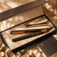 Hair straightener flat iron with black body and gold plates inside open box