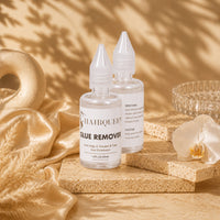 Hair Queen LA glue remover bottles (2) on stone blocks, clear caps and labels.