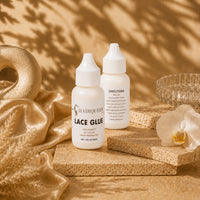 Hair Queen LA Lace Glue bottles on stacked beige stones with satin fabric