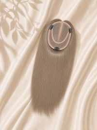 Close-up of light ash blonde mono base with clips and attached straight hair.