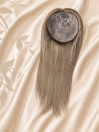 Circular silk base topper with embedded gray net and long straight hair.