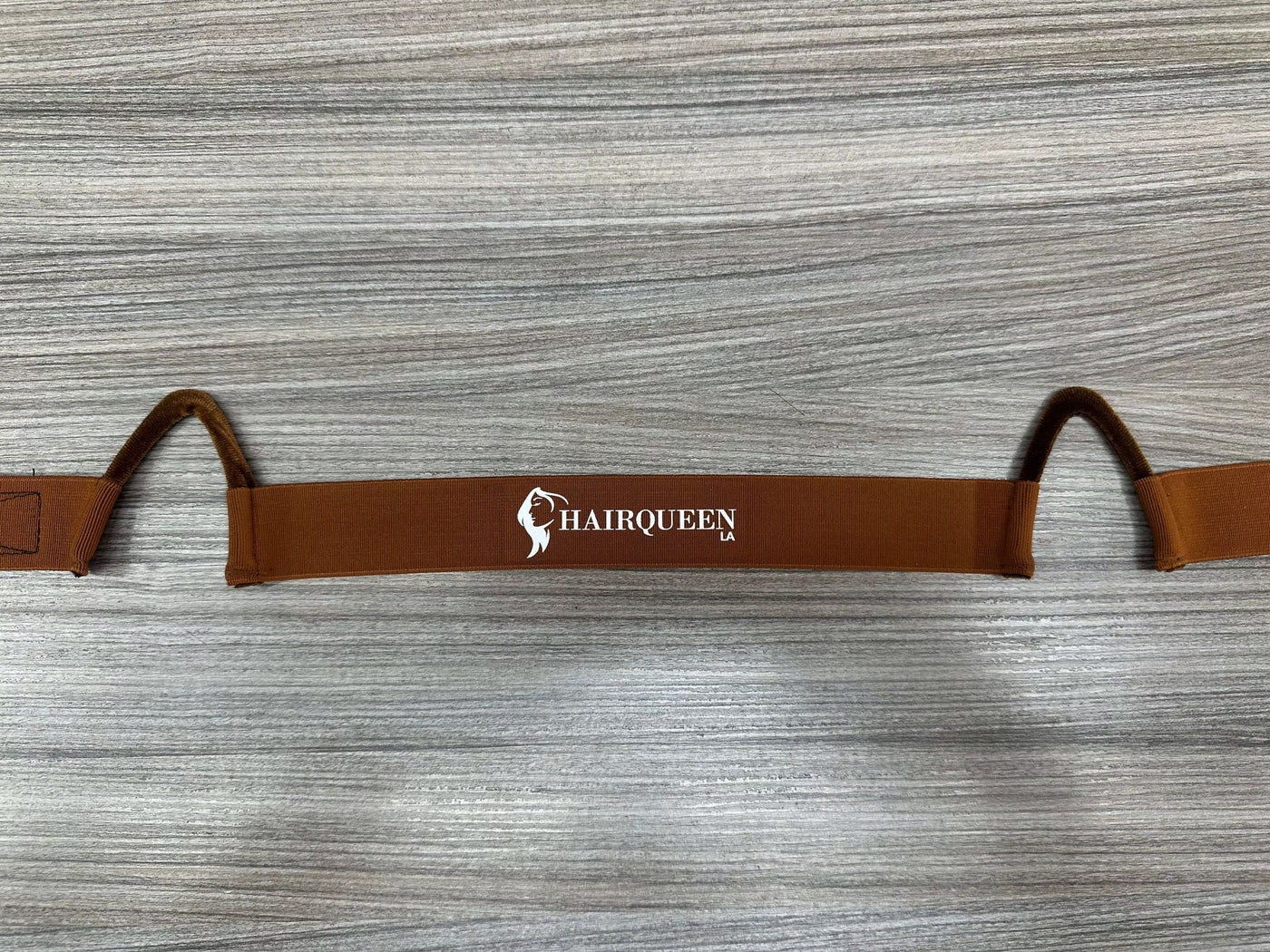 Brown wig band with HairQueen logo and two curved end loops for securing