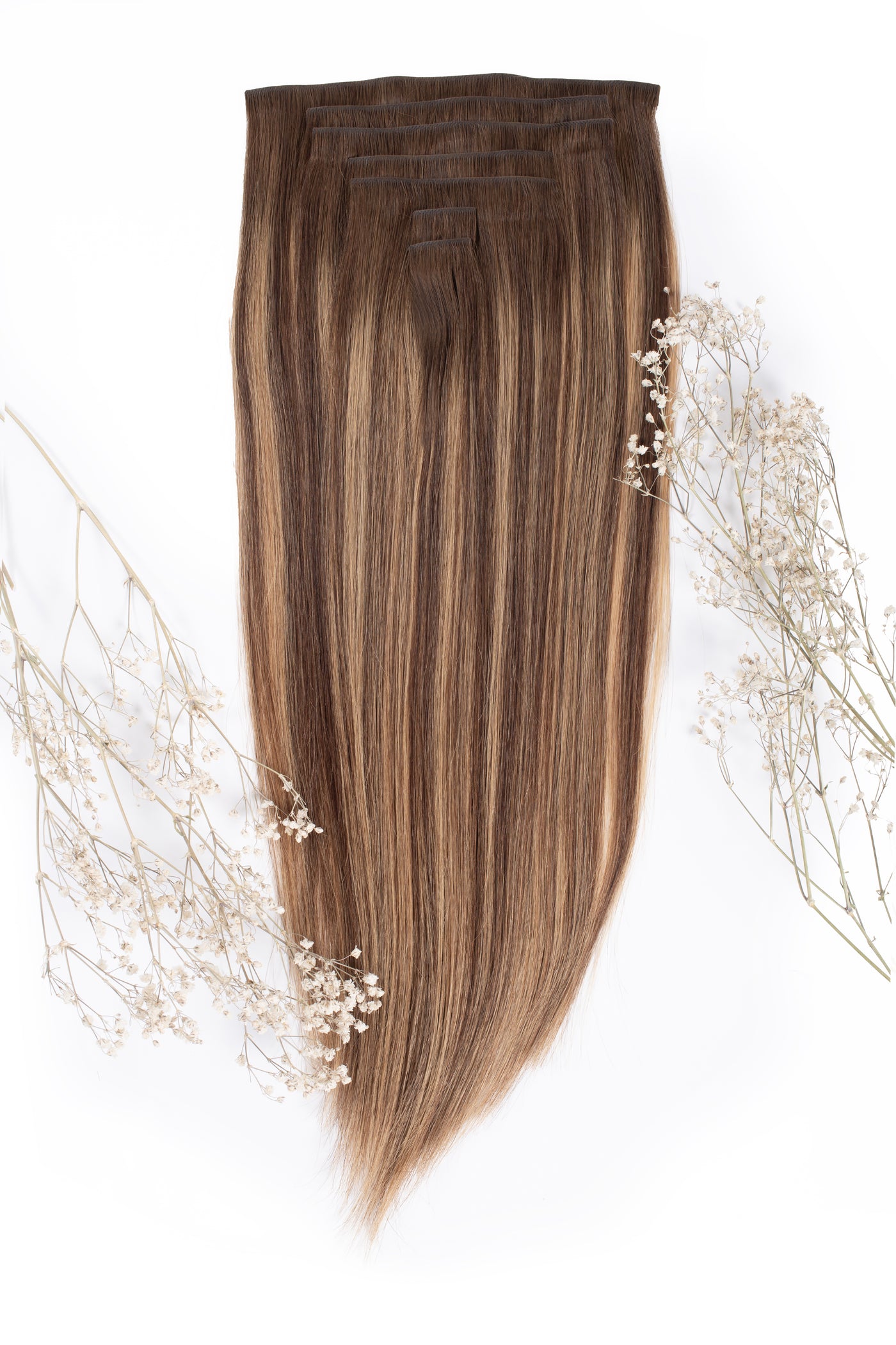 Caramel blend clip-in hair extensions with snap clips along the top edge, straight hair