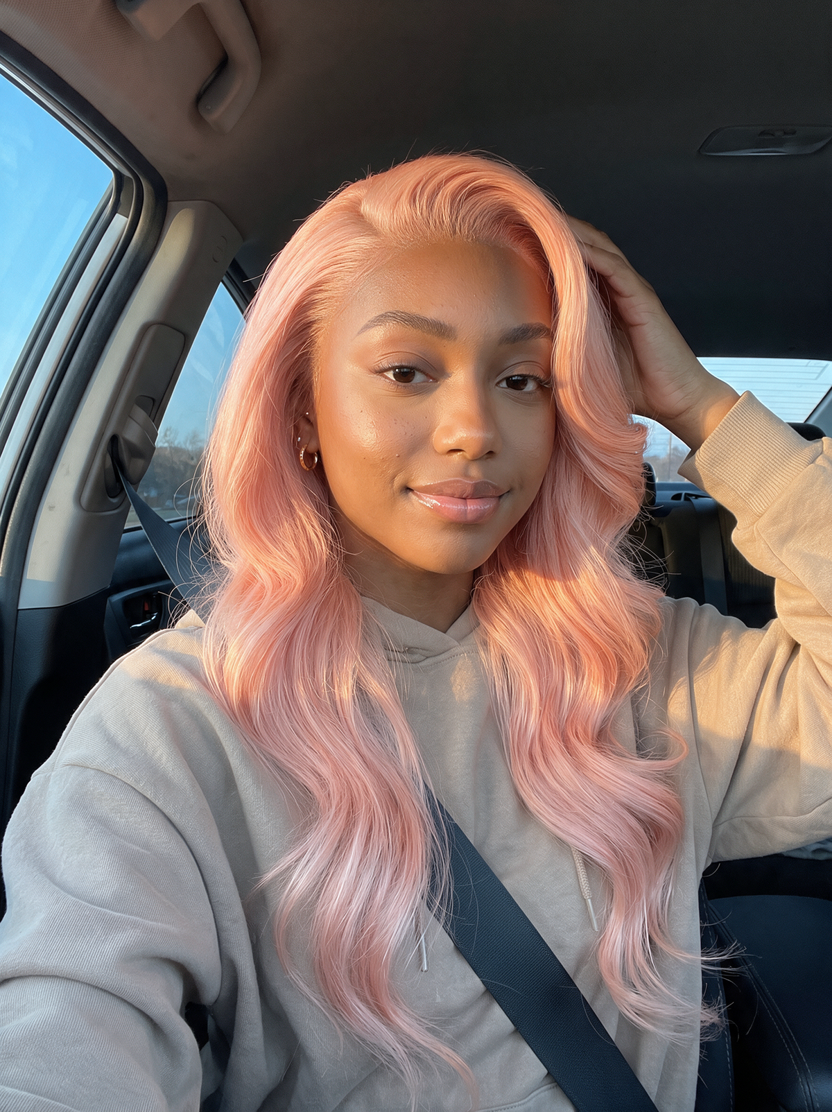 Light pink wavy wig with natural hairline, worn at shoulder length, center part.