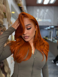 Long wavy ginger-orange lace wig with side part, full volume around crown