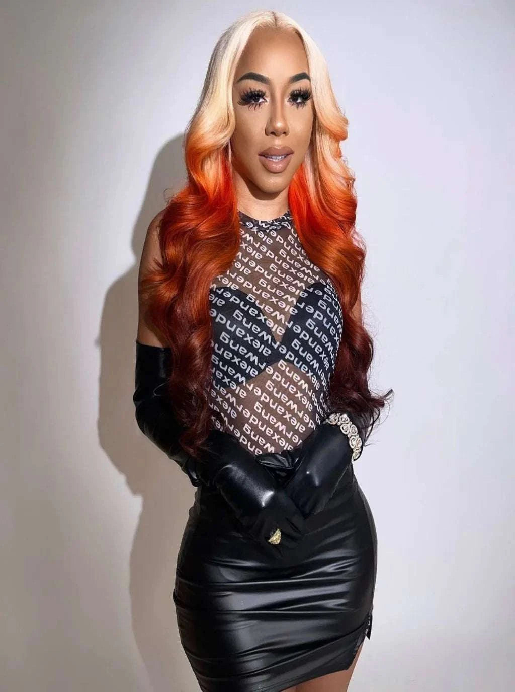 Long wavy wig with blonde top and copper-orange ends, styled smooth.