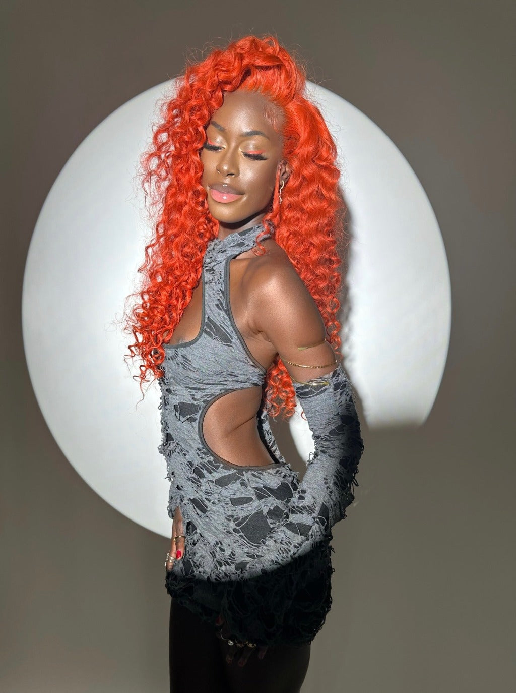 Bright orange curly wig with long voluminous curls and side-swept volume