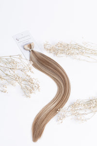 Invisible tape-in hair extension weft in blonde blend with long straight strands and tape