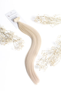 Platinum blonde hair extension strand with tape weft end