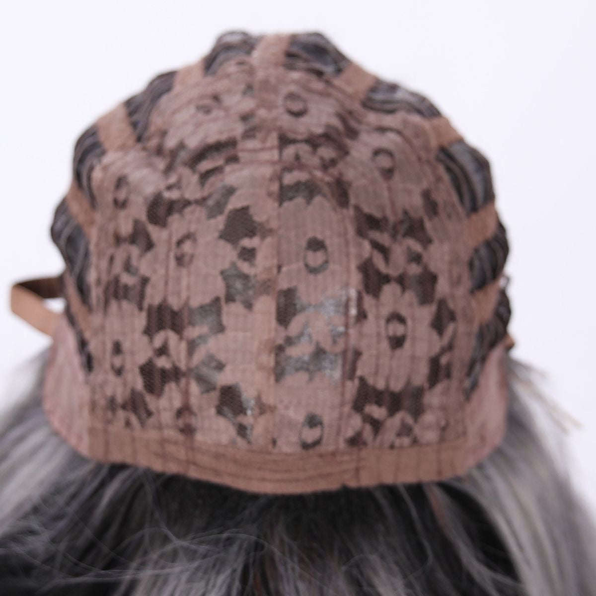 Synthetic wig cap closeup with light gray fabric and dark speckled pattern