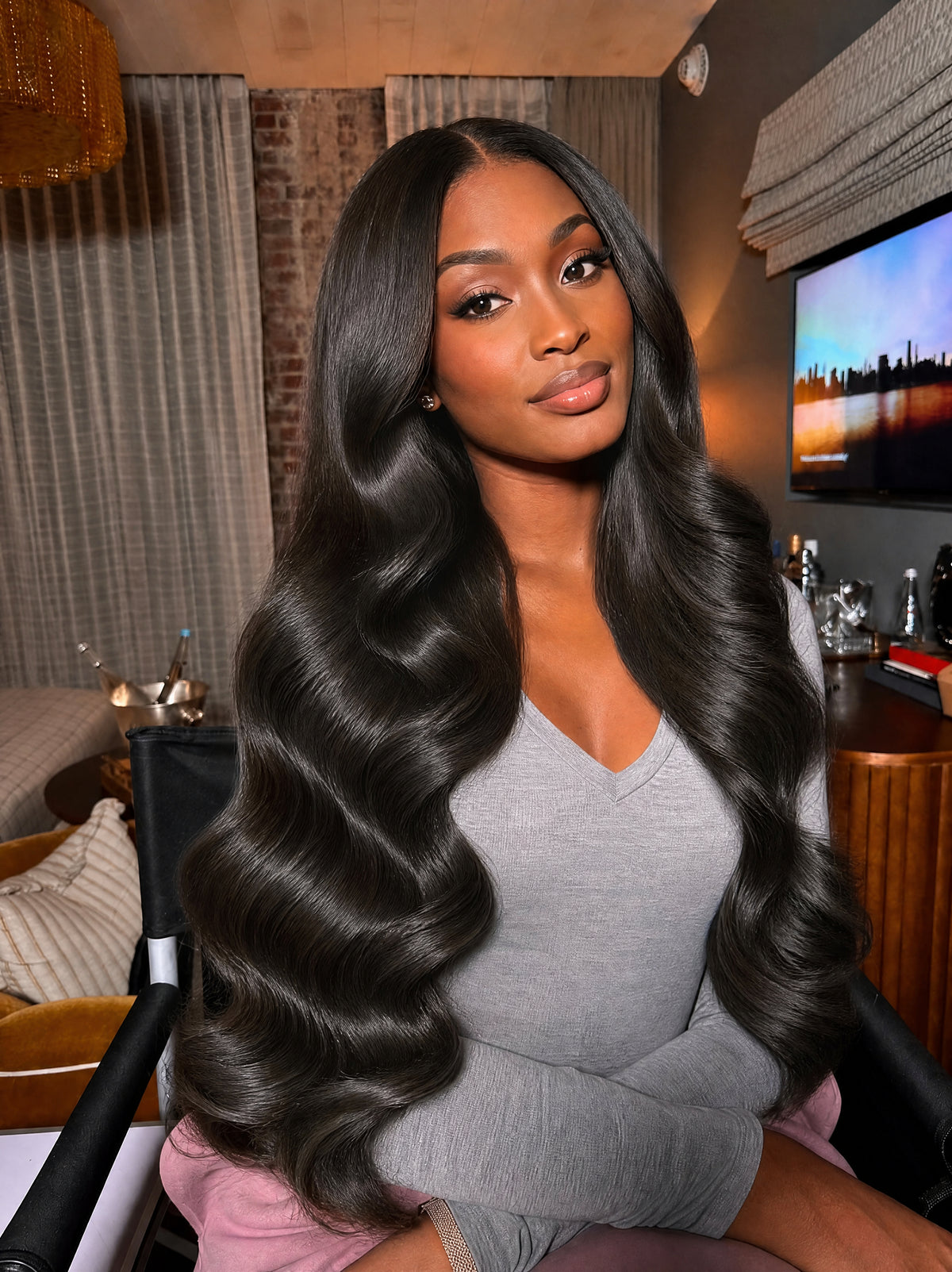 Black wavy hair bundle on model, long loose waves framing the shoulders.