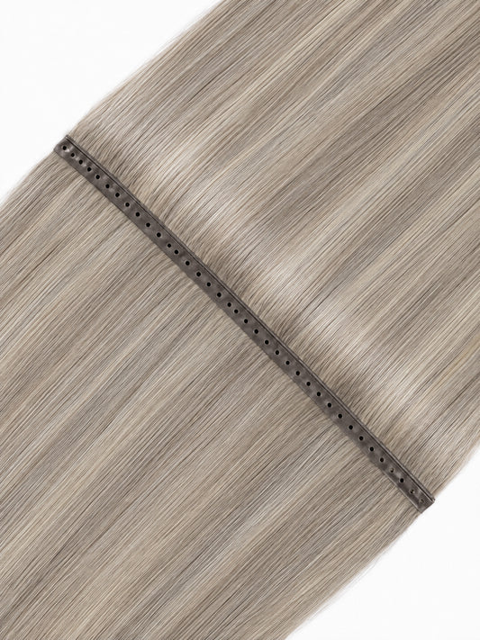 Light ash blonde hair weft extension with perforated dark track and smooth strands.