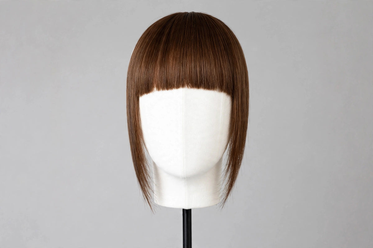 Straight dark brown bangs on mannequin head, blunt fringe across forehead