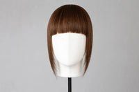 Straight dark brown bangs on mannequin head, blunt fringe across forehead