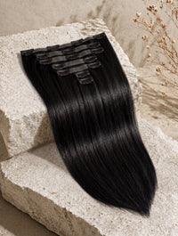 Seamless clip-in hair extension weft with straight, silky black hair and comb clips
