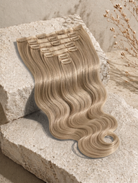 Ash blonde wavy clip-in hair extensions with multiple comb clips on a swatch