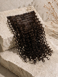 Seamless clip-in hair extension with tight curly texture and clip band top.