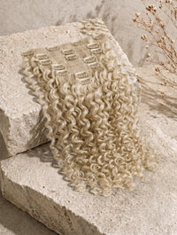 Curly seamless clip-in extensions in light blonde with multiple wefts and clip bases