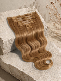 Wavy light brown clip-in hair extensions weft with comb clips attached.