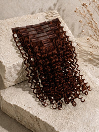Curly dark brown clip-in hair extension piece with multiple black barrette clips
