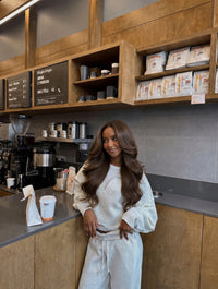 Seamless clip-in hair extensions on model, long wavy medium-brown hair in cafe setting