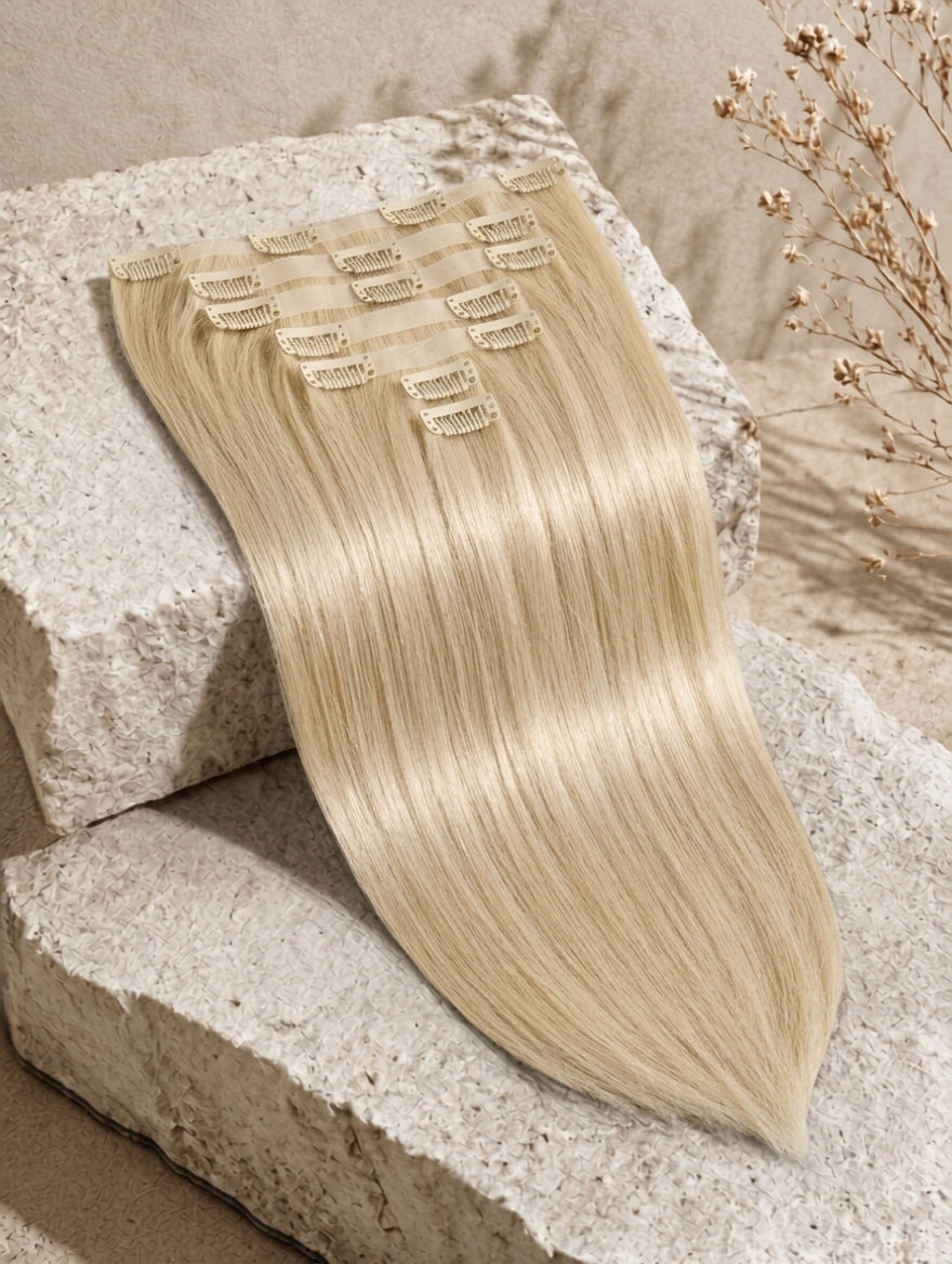 Blonde clip-in hair extension weft with rows of metal clips and straight silky strands