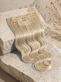 Wavy blonde clip-in hair extension weft with multiple metal snap clips and flowing hair