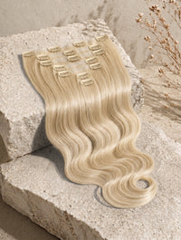 Honey blonde clip-in hair extension weft with black comb clips and loose waves